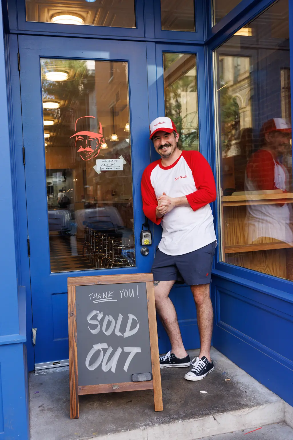Salt Hank stands next to a Sold Out sign in front of his New York City sandwich shop.